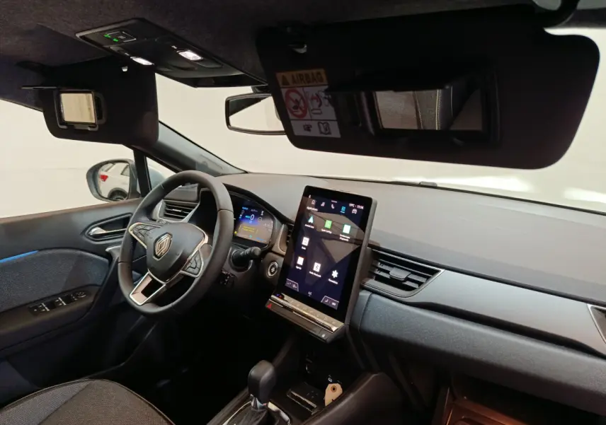 Intérieur du Renault Captur blanc 2025, vue côté conducteur, tableau de bord avec écran tactile vertical et volant multifonctions.