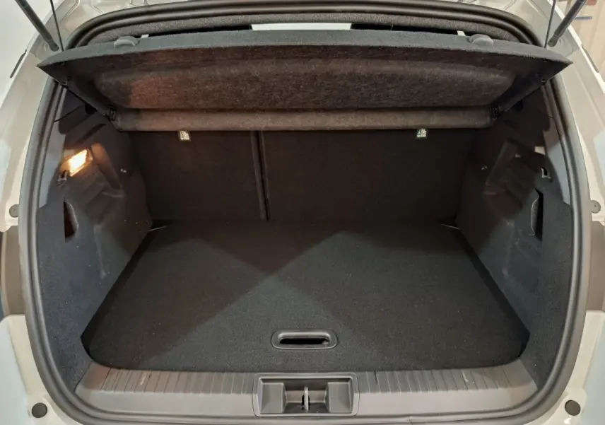 Coffre ouvert vu de l'arrière d'un Renault Captur blanc 2025, intérieur noir avec éclairage latéral allumé.