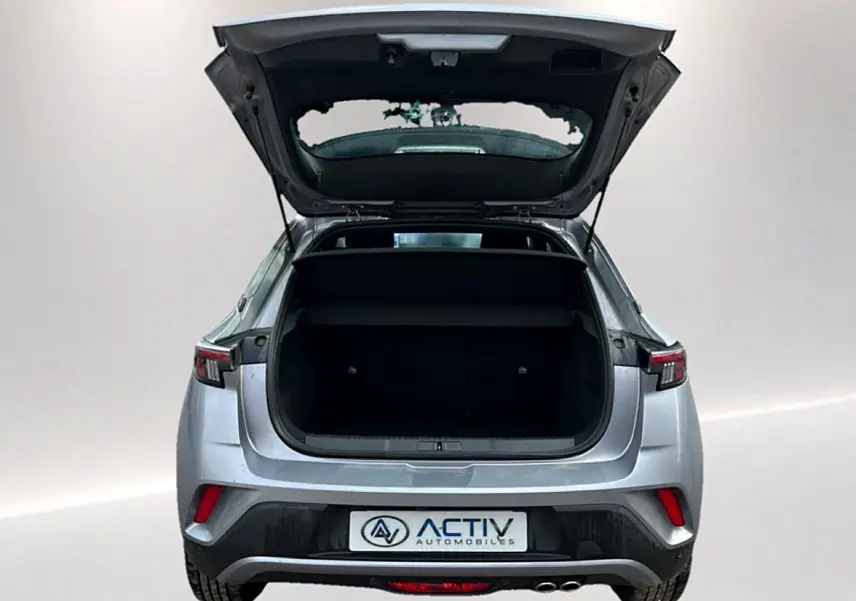 Vue arrière d’un Opel Mokka gris 2025 avec le coffre ouvert, feux arrière LED et double sortie d’échappement visible.