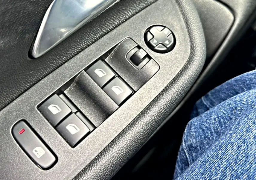Gros plan sur les commandes de lève-vitres et rétroviseurs côté gauche intérieur d’un Opel Mokka gris 2025.