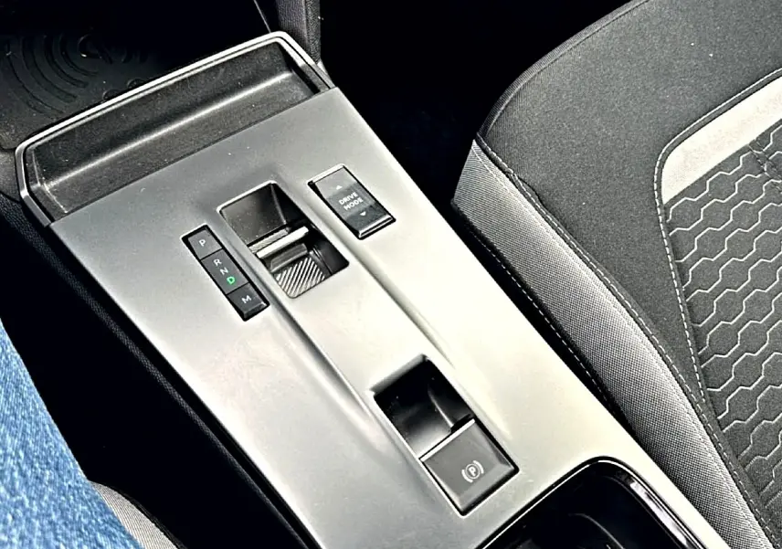 Vue rapprochée de la console centrale grise avec levier de vitesses automatique et siège tissu noir Opel Mokka 2025.