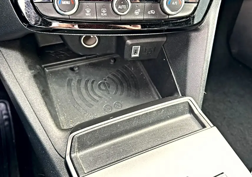 Détail de la console centrale noire de l’Opel Mokka 2025 avec zone de recharge sans fil et commandes de climatisation.