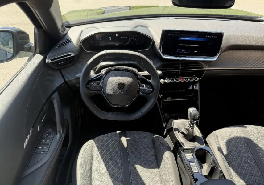 Vue intérieure avant du Peugeot 2008 2025, tableau de bord moderne avec volant compact et levier de vitesse manuel.