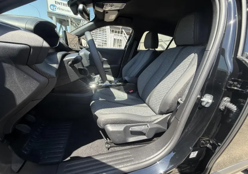 Intérieur du Peugeot 2008 2025 noir perla, vue côté gauche avant montrant les sièges tissu et le tableau de bord.