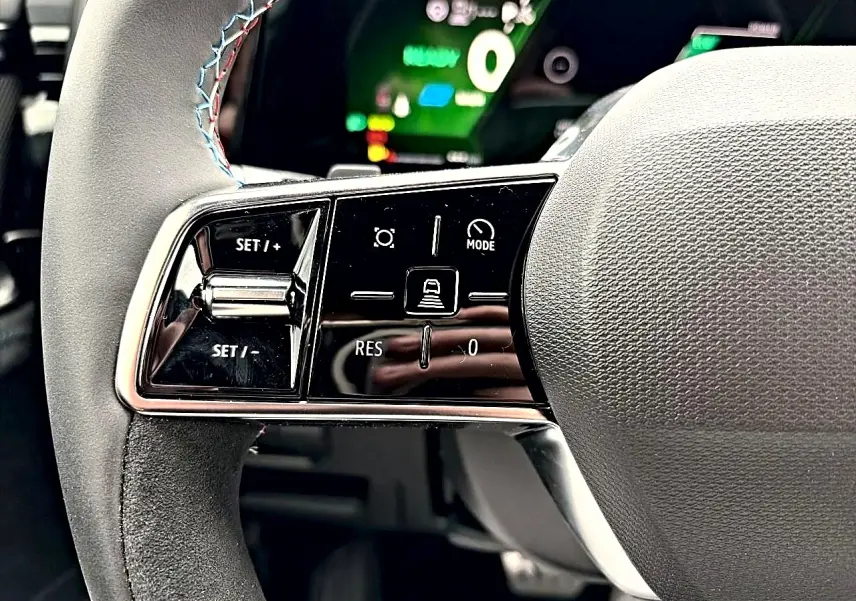 Gros plan sur les commandes noires brillantes au volant du Renault Austral 1.2 e-tech gris schiste, avec surpiqûres tricolores.