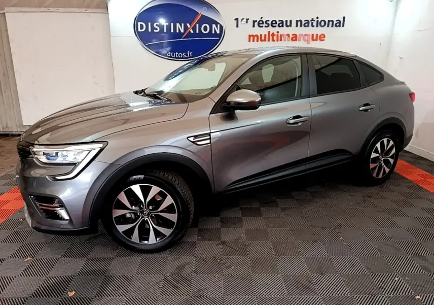 Renault Arkana Business E-TECH 145 gris foncé vu de profil côté gauche dans un showroom avec logo Distinxion en arrière-plan