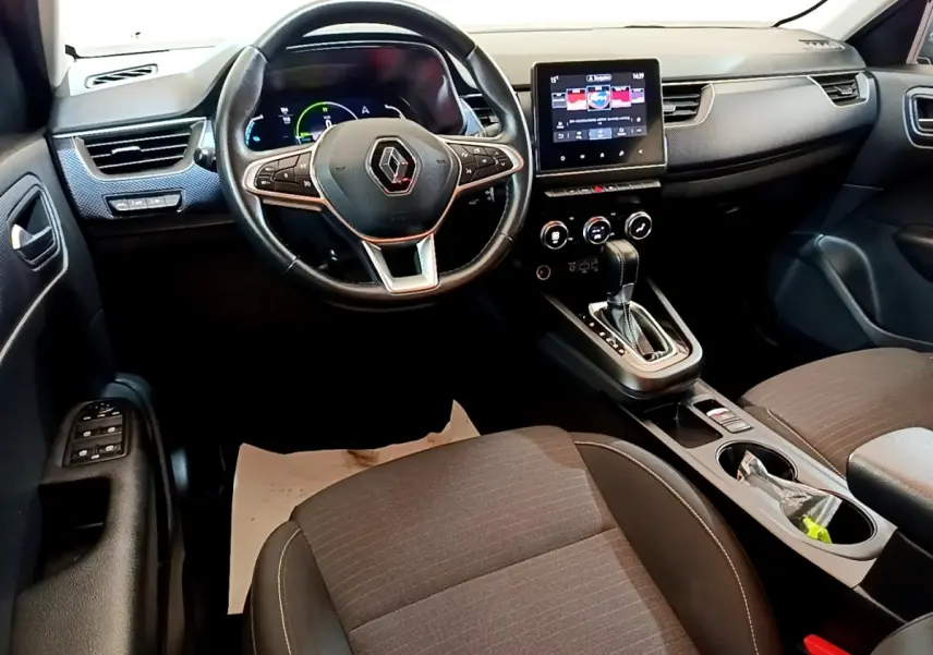 Vue intérieure avant du Renault Arkana Business E-TECH 145, tableau de bord noir avec écran tactile central et volant multifonctions.