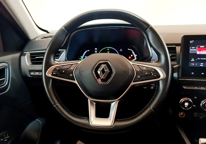 Volant en cuir noir avec logo Renault au centre, tableau de bord numérique et écran tactile à droite dans Renault Arkana Business E-TECH.