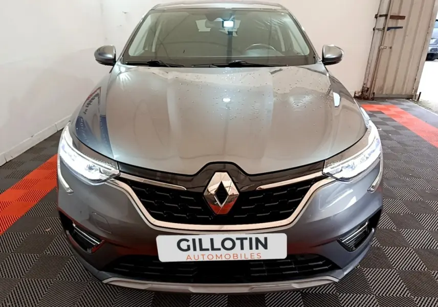 Vue frontale d'un Renault Arkana Business E-TECH 145 gris foncé avec phares LED allumés en intérieur.