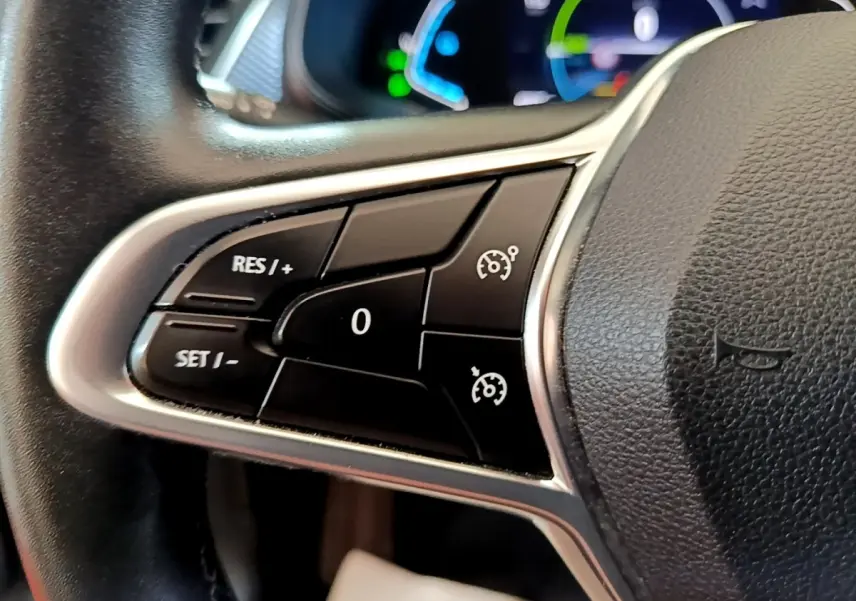 Gros plan sur les commandes du régulateur de vitesse au volant cuir du Renault Arkana Business E-TECH gris foncé 2022.