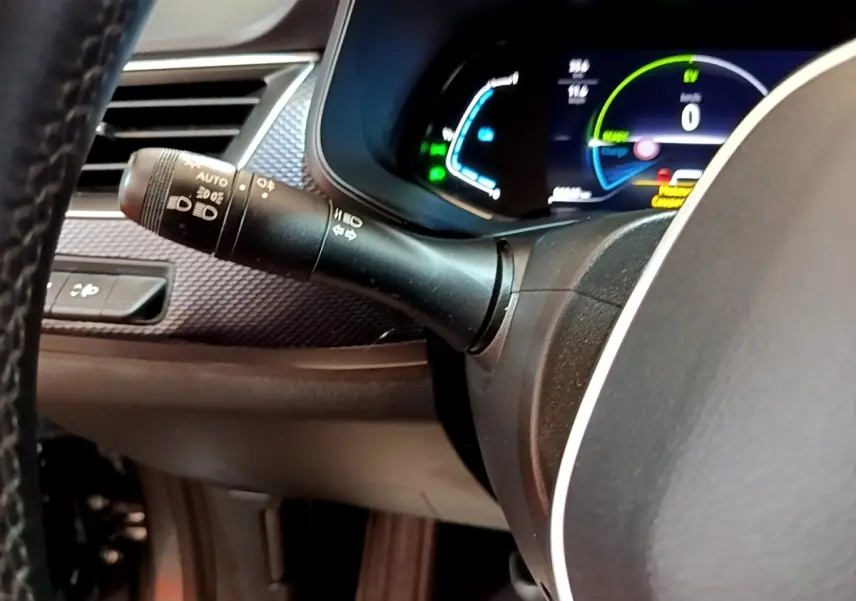 Gros plan sur la manette de phares à gauche du volant et le combiné d'instruments numérique du Renault Arkana Business E-TECH 145.