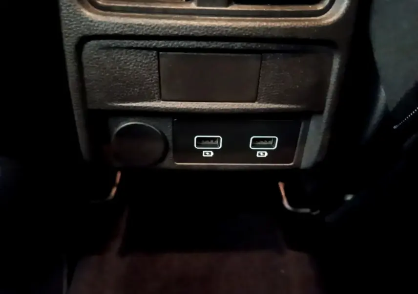 Prise USB double et prise 12V noire sous la console centrale du Renault Arkana Business E-TECH 145 gris foncé.