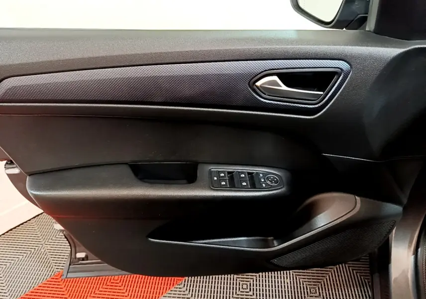 Vue intérieure côté gauche de la porte conducteur du Renault Arkana Business E-TECH 145 avec commandes électriques et poignée argentée.