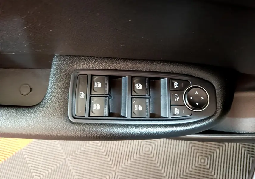 Gros plan sur les commandes de lève-vitres et rétroviseurs sur la porte intérieure d'une Renault Arkana gris foncé.