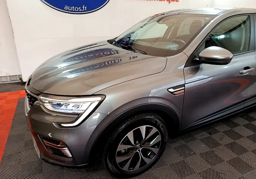 Vue 3/4 avant droit d'un Renault Arkana Business E-TECH gris foncé avec jantes alliage et feux LED distinctifs.