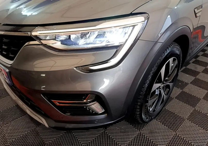 Gros plan sur l'avant droit gris foncé du Renault Arkana Business E-TECH 145, mettant en valeur le phare LED et la roue.