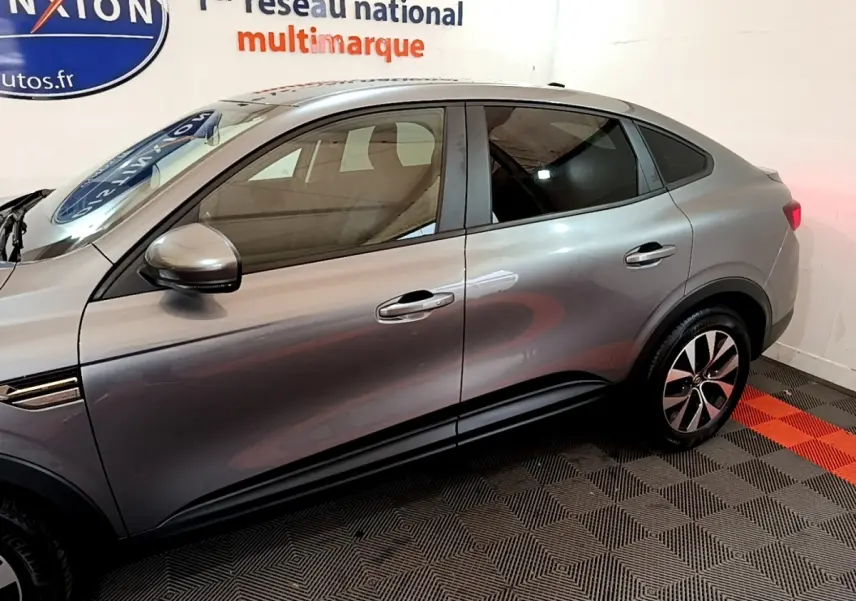 Profil côté gauche d'un Renault Arkana Business E-TECH 145 gris foncé avec jantes alliage et rétroviseurs intégrés.