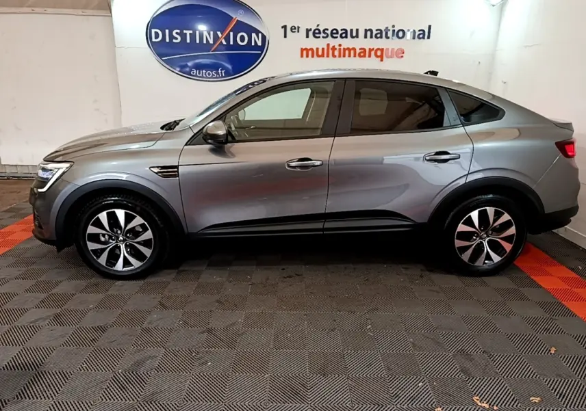 Profil côté gauche d'une Renault Arkana Business E-TECH 145 gris foncé, avec jantes alliage et lignes fluides du SUV coupé.