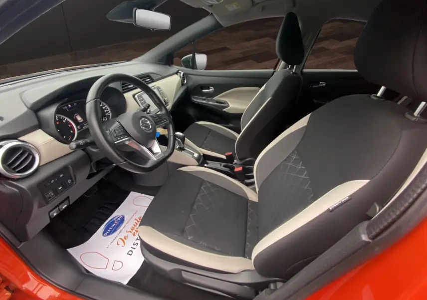 Vue intérieure côté conducteur de la Nissan Micra orange energy 2022, sièges tissu noir et beige avec volant multifonction.