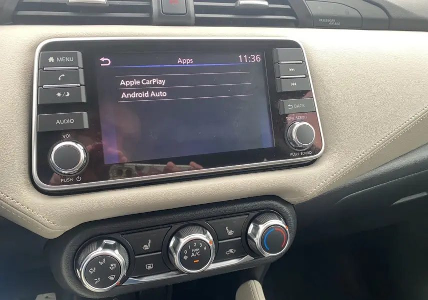 Vue rapprochée de la console centrale de la Nissan Micra 2022 avec écran tactile et commandes de climatisation beige et noir.