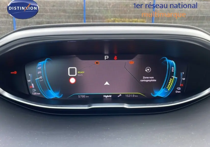 Vue rapprochée du tableau de bord numérique du Peugeot 3008 hybride, affichant la charge et la vitesse en mode prêt.