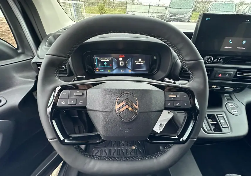 Vue rapprochée du volant cuir noir du Citroën Berlingo 2025 avec tableau de bord numérique et écran central tactile.