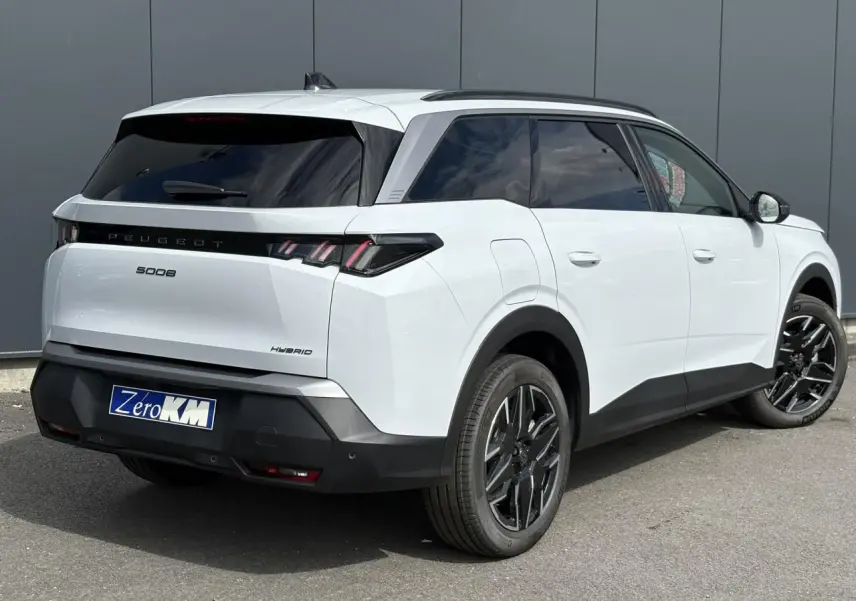 Vue 3/4 arrière droite d'un Peugeot 5008 Hybrid blanc Okénite avec jantes alliage noires et vitres teintées.