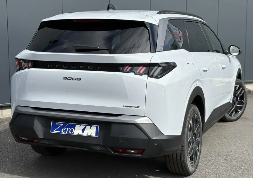Vue 3/4 arrière droite d'un Peugeot 5008 Hybrid blanc Okénite avec feux arrière LED 3 griffes et jantes alliage noires.