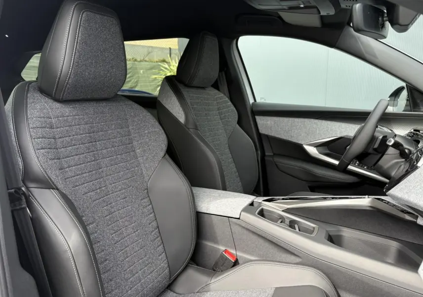 Vue intérieure côté conducteur du Peugeot 5008 Hybrid 145 e-DSC6 Allure 7 places, sièges tissu gris et cuir noir, tableau de bord moderne.