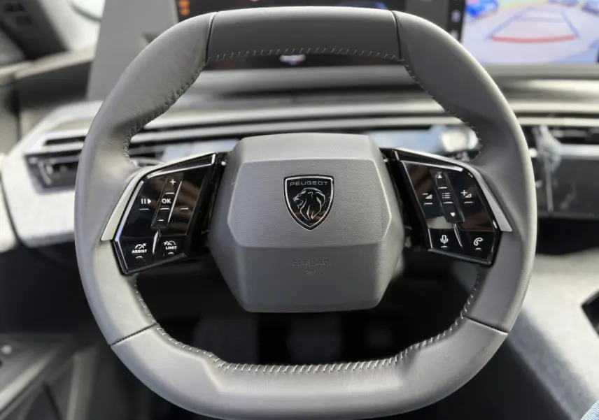 Volant compact gris du Peugeot 5008 Hybrid 145 e-DSC6 Allure 2025 avec commandes intégrées noir laqué.