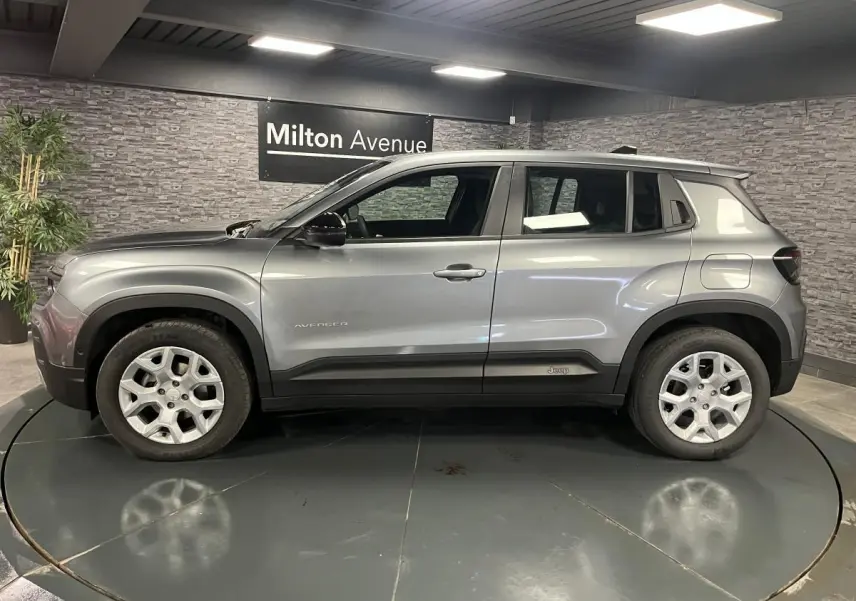 Profil côté gauche du Jeep Avenger gris métallisé 2024 avec jantes alliage et coques de rétroviseurs noires.