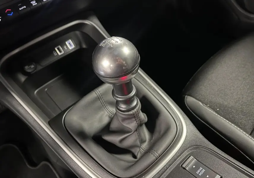 Gros plan sur le levier de vitesses manuel en TEP noir du Jeep Avenger 2024, avec console centrale et prise USB visible.