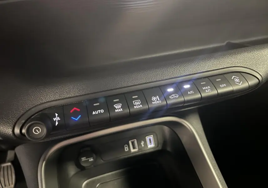 Gros plan sur la console centrale du Jeep Avenger 2024 montrant les commandes de climatisation et ports USB.