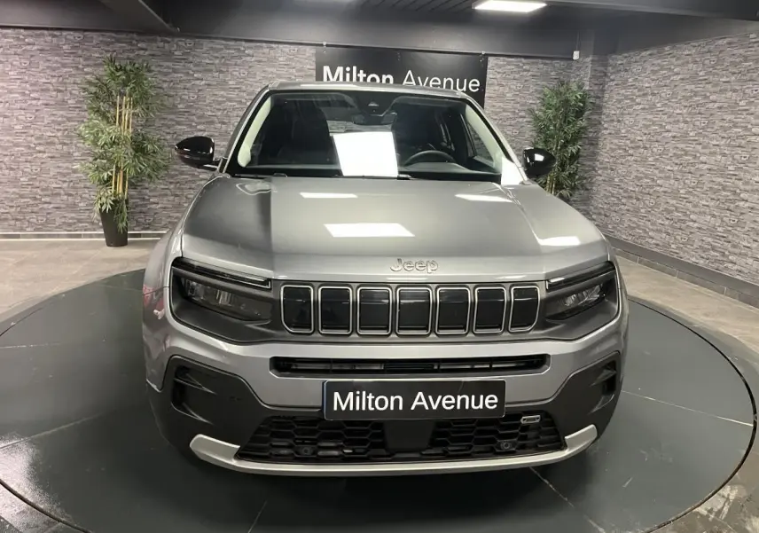 Vue frontale du Jeep Avenger gris métallisé avec calandre distinctive et coques de rétroviseurs noires brillantes.