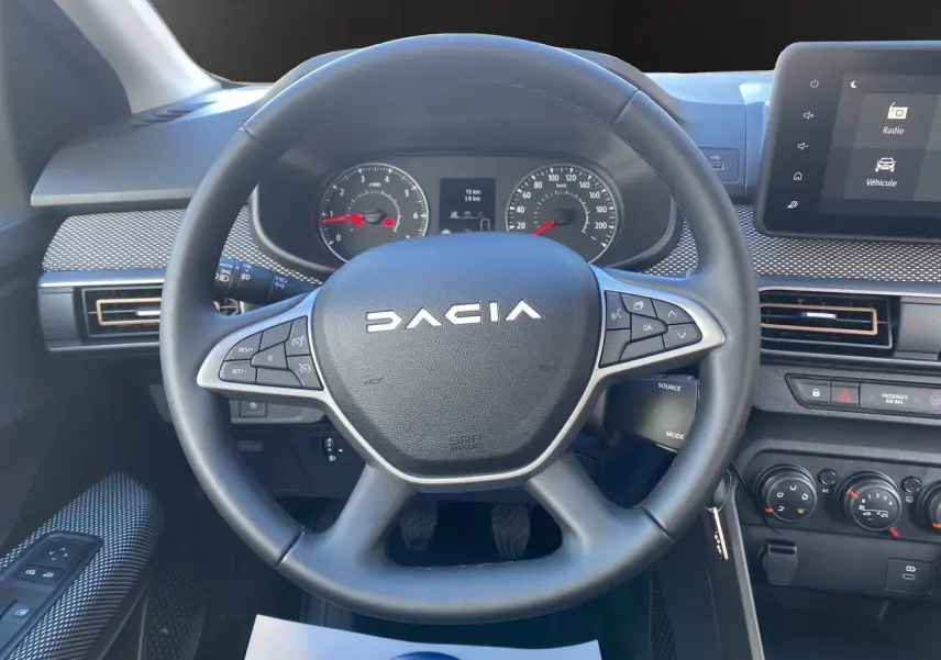 Vue rapprochée du volant noir DACIA avec tableau de bord et écran tactile du Media Nav en arrière-plan.