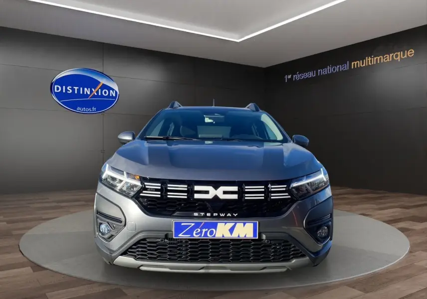 Vue frontale d'une Dacia Sandero Stepway gris schiste avec calandre noire et logo distinctif, en showroom.