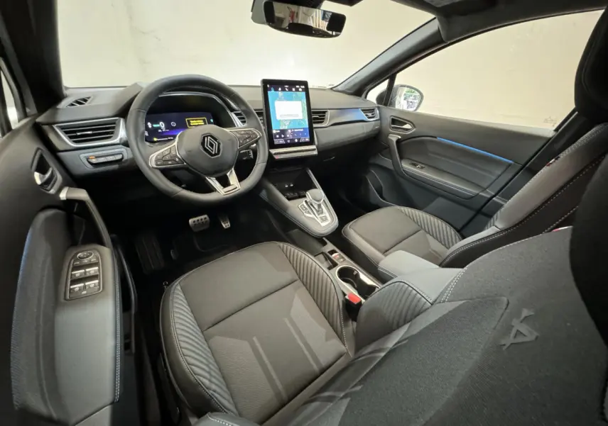 Vue intérieure côté conducteur du Renault Captur esprit Alpine E-Tech 2025, sièges noirs et écran tactile vertical central.