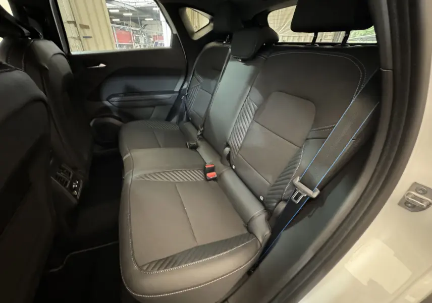 Vue intérieure côté droit montrant la banquette arrière noire avec surpiqûres bleues du Renault Captur blanc esprit Alpine E-Tech 2025.