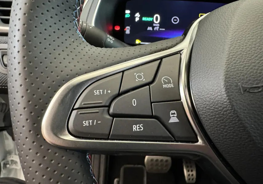 Gros plan sur les commandes du volant cuir perforé du Renault Captur blanc esprit Alpine E-Tech 2025, avec affichage numérique.