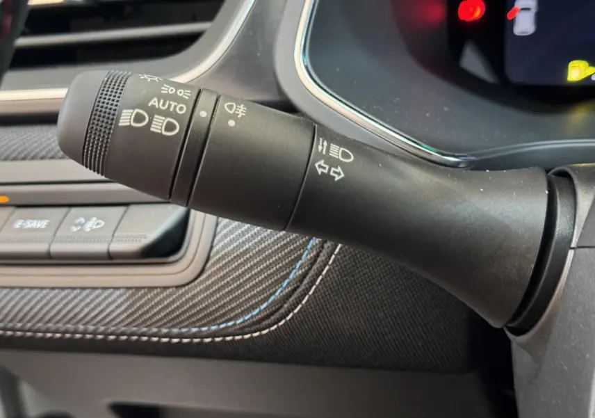 Gros plan sur la commande des feux et clignotants dans l'habitacle du Renault Captur blanc esprit Alpine E-Tech 2025.