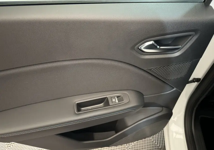 Gros plan sur la porte intérieure côté gauche du Renault Captur blanc, avec surpiqûres bleues et bouton de verrouillage.