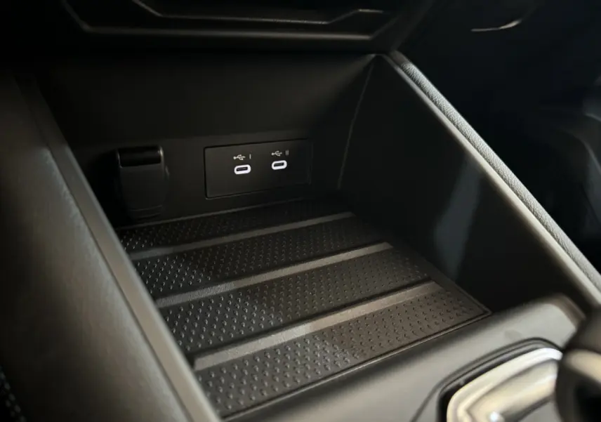 Gros plan sur la zone de recharge et ports USB doubles dans le coffre central du Renault Captur blanc esprit Alpine E-Tech 2025.