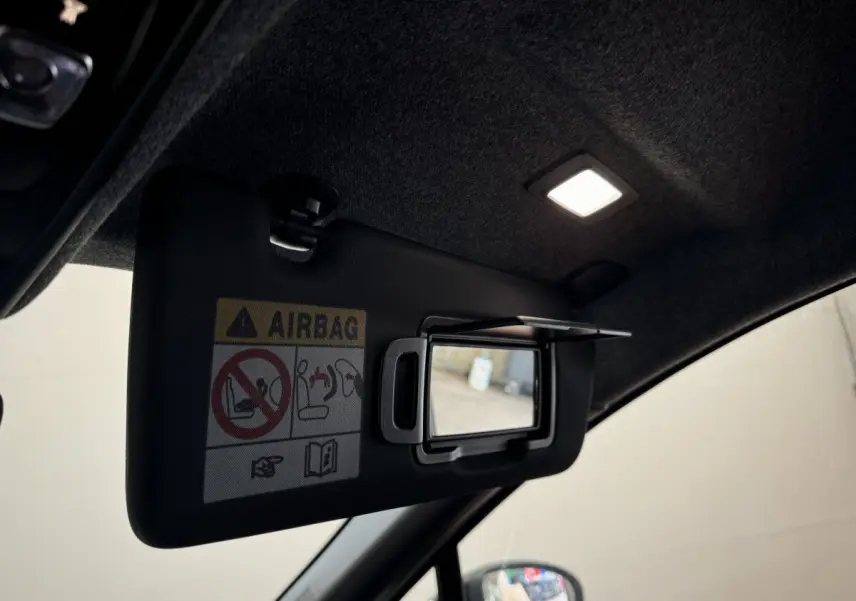 Détail du pare-soleil côté conducteur avec miroir éclairé dans l'habitacle noir du Renault Captur blanc 2025.
