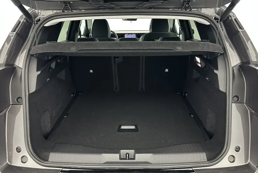 Coffre ouvert vu de l'arrière d'un Citroën C5 Aircross hybride gris platinium, montrant un espace de chargement vide et spacieux.