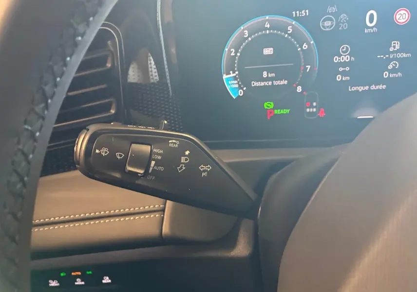 Gros plan sur la manette de commandes au volant du Volkswagen Tiguan noir Grenadilla, avec tableau de bord numérique en arrière-plan.