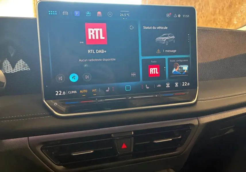 Vue rapprochée de l’écran tactile central du Volkswagen Tiguan noir Grenadilla 2026 avec interface radio RTL et climatisation affichée.