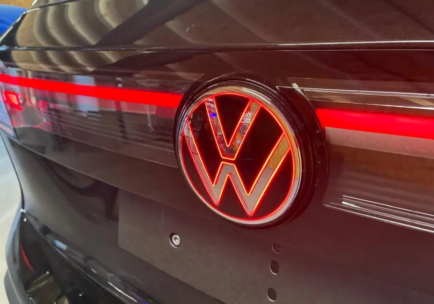 Gros plan sur l'arrière noir grenadilla métal du Volkswagen Tiguan 2026 avec logo VW lumineux rouge et bande LED.