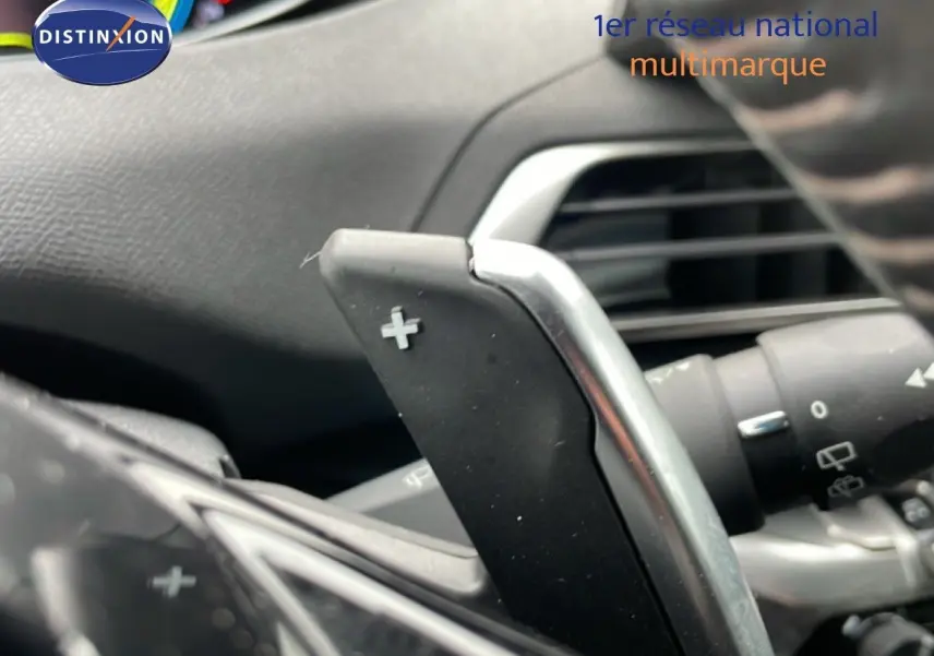 Gros plan sur la palette de changement de vitesse + au volant d’un Peugeot 3008 gris Artense 2024 hybride rechargeable.
