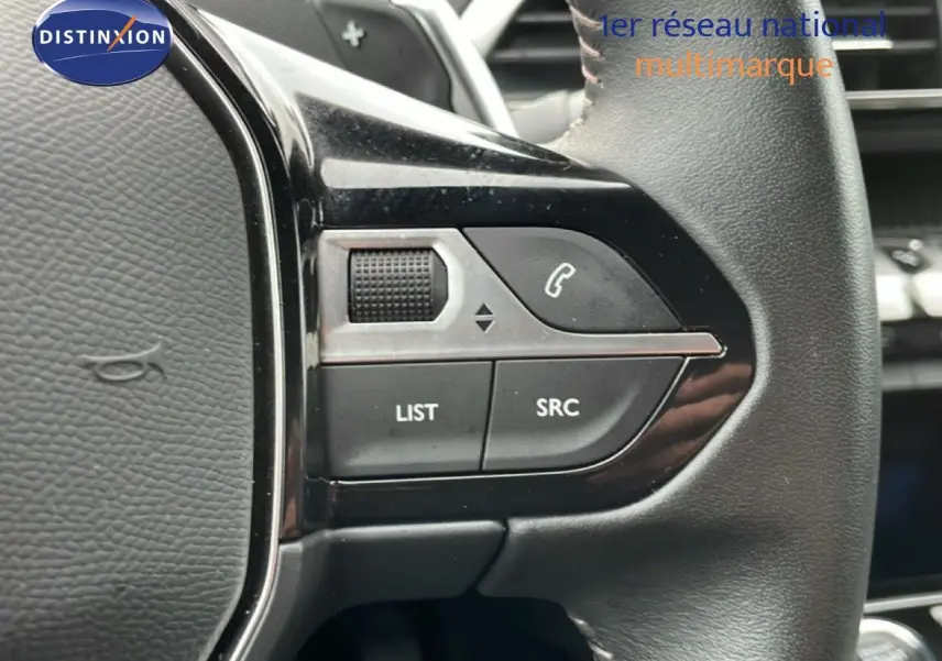 Gros plan sur les commandes gauche du volant cuir noir du Peugeot 3008 gris Artense 2024, boutons LIST et SRC visibles.