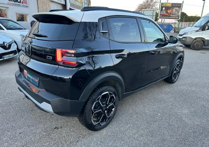 Vue 3/4 arrière droite d'une Citroën C3 noire 2025 avec barres de toit et jantes alliage 17 pouces.